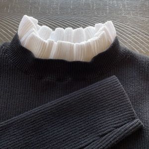 Black knit shirt with white collar.